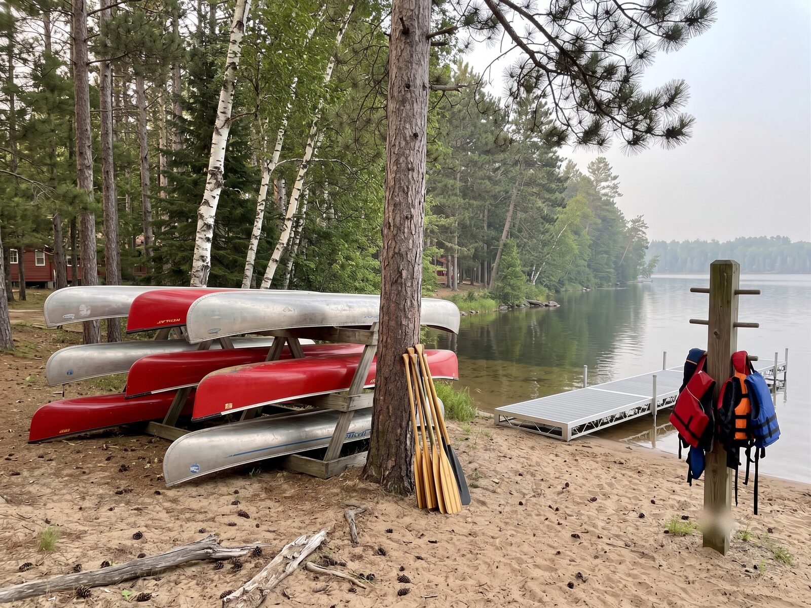 Wenonah canoes stacked on the shoreline rack, paddles leaning alongside