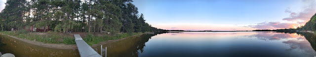The dock walkway curving past the forested point under a pastel sunset
