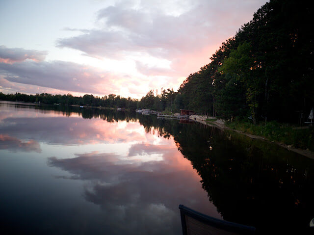A fiery sunset burning through the pines and reflecting on still water