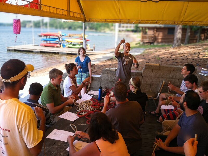 An instructor teaching campers knots on the dock, ropes across every lap